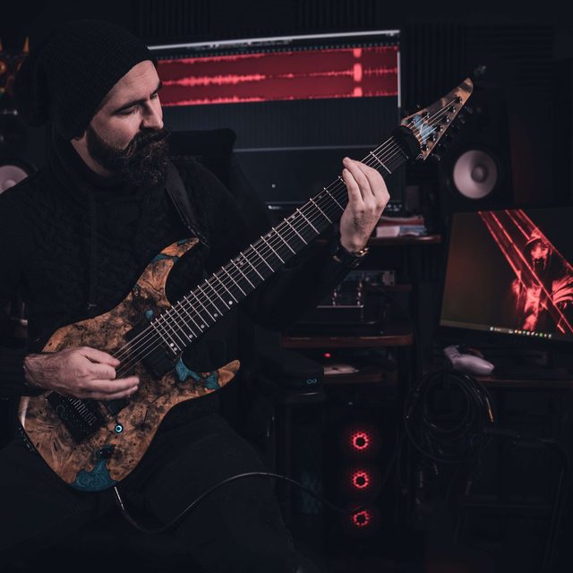 Coach Frank playing an electric guitar in a studio
