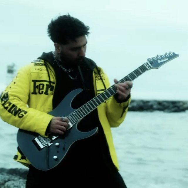 Coach Mike playing guitar on the rocks by the ocean